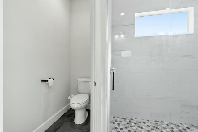 bathroom with tile patterned flooring, toilet, and a tile shower