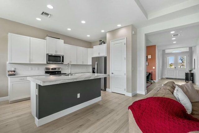 kitchen featuring a center island with sink, white cabinets, stainless steel appliances, and french doors