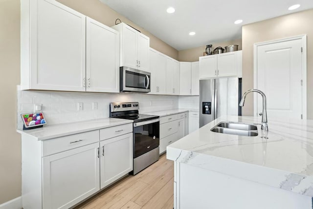 kitchen featuring light stone countertops, sink, white cabinetry, and stainless steel appliances