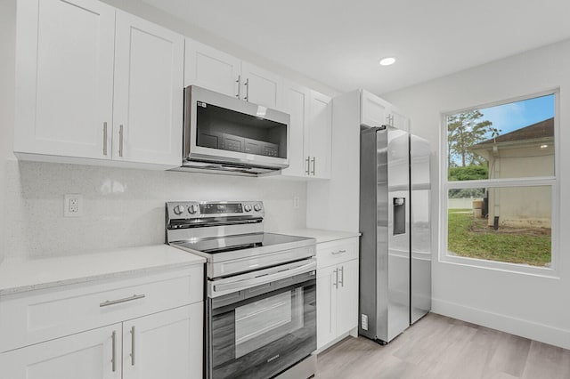 kitchen featuring a healthy amount of sunlight, light hardwood / wood-style flooring, white cabinets, and stainless steel appliances