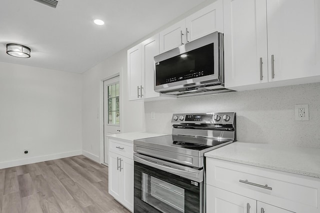 kitchen with backsplash, white cabinets, light hardwood / wood-style flooring, light stone countertops, and stainless steel appliances