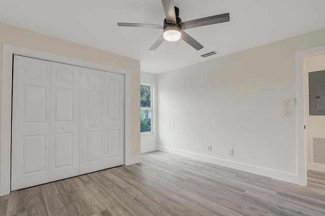 unfurnished bedroom featuring light wood-type flooring, a closet, ceiling fan, and electric panel