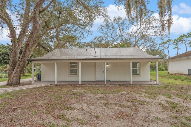 rear view of house featuring covered porch and a lawn