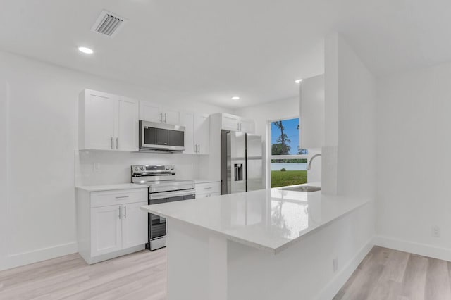 kitchen featuring white cabinets, sink, stainless steel appliances, and light hardwood / wood-style flooring