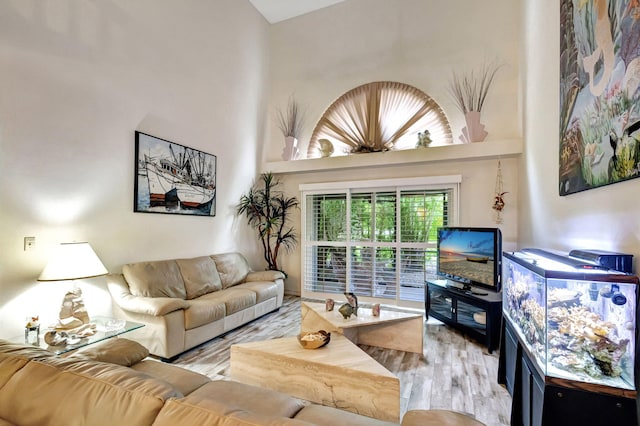 living room with a towering ceiling and light wood-type flooring