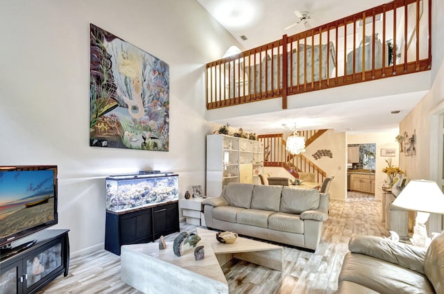 living room featuring ceiling fan with notable chandelier, light wood-type flooring, and high vaulted ceiling