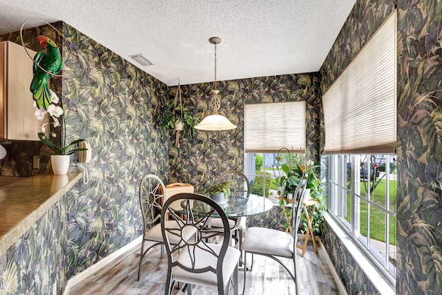 dining area with hardwood / wood-style floors and a textured ceiling