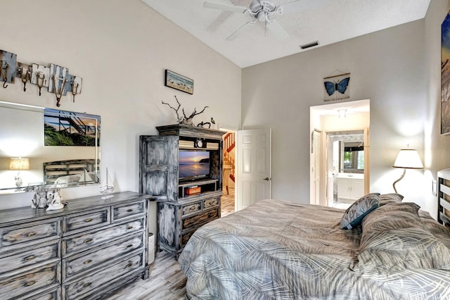 bedroom featuring lofted ceiling, ensuite bathroom, ceiling fan, a textured ceiling, and light hardwood / wood-style floors