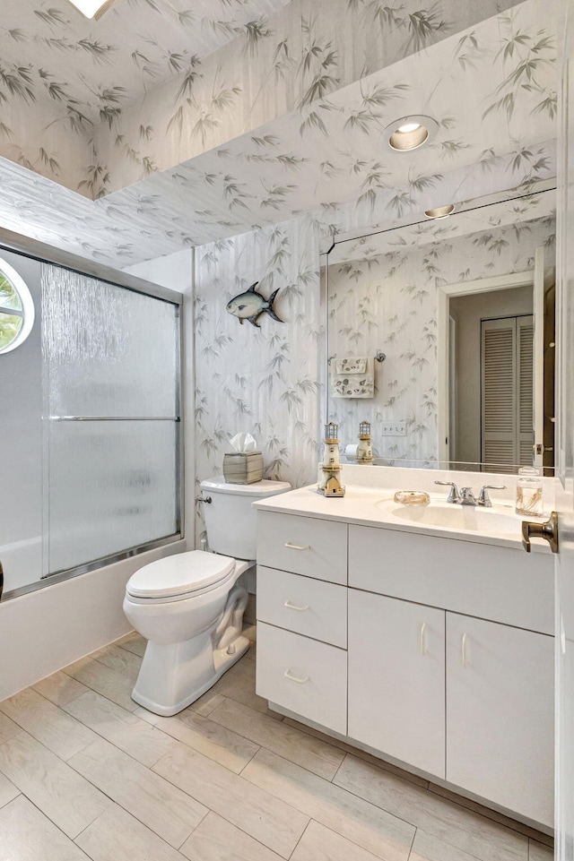 full bathroom featuring shower / bath combination with glass door, vanity, hardwood / wood-style flooring, and toilet