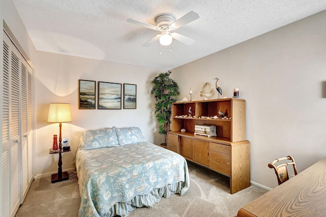 bedroom featuring a textured ceiling, light colored carpet, a closet, and ceiling fan