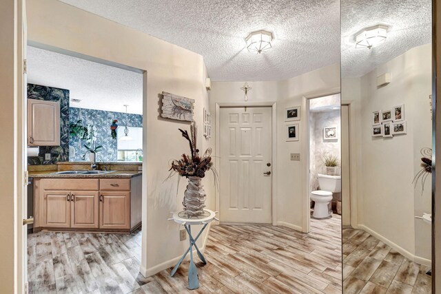 foyer featuring a textured ceiling, light wood-type flooring, and sink