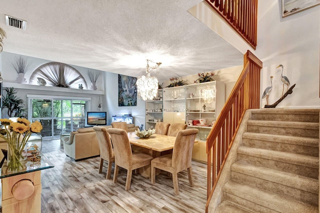 dining space featuring light hardwood / wood-style floors, a textured ceiling, and a chandelier