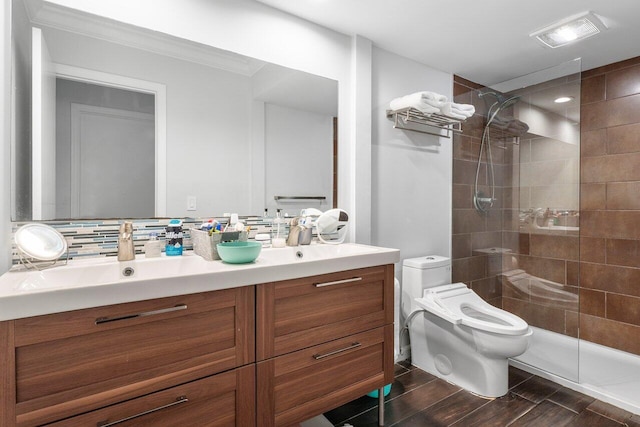 bathroom featuring a tile shower, decorative backsplash, vanity, and toilet