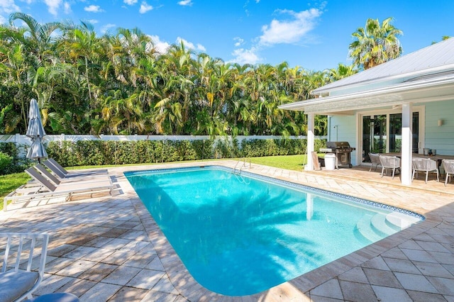 view of swimming pool featuring ceiling fan, a patio, and grilling area