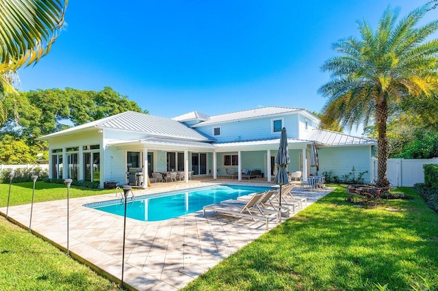 back of property featuring a fenced in pool, a yard, and a patio