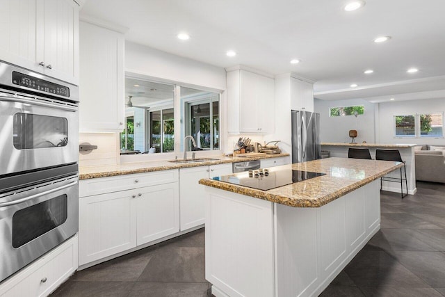 kitchen featuring white cabinetry, light stone countertops, sink, and appliances with stainless steel finishes