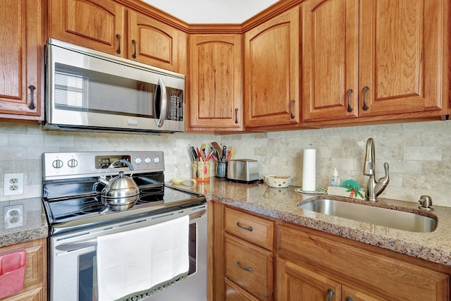 kitchen with light stone counters, sink, appliances with stainless steel finishes, and tasteful backsplash