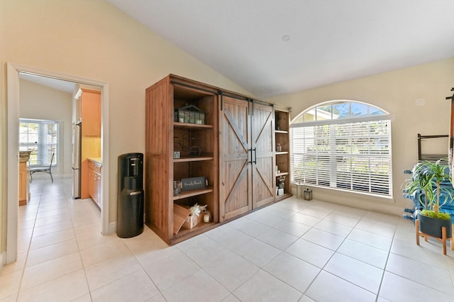 interior space featuring light tile patterned floors, vaulted ceiling, and plenty of natural light