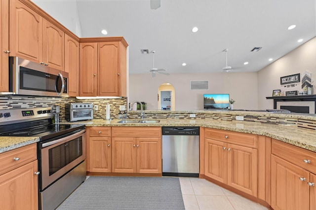 kitchen featuring ceiling fan, sink, light stone countertops, stainless steel appliances, and tasteful backsplash