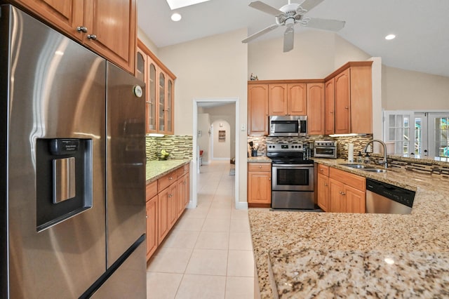 kitchen with sink, ceiling fan, decorative backsplash, light stone counters, and stainless steel appliances