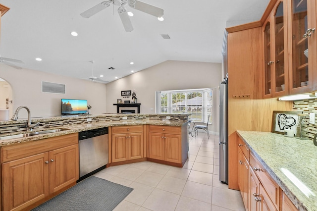 kitchen featuring light stone countertops, sink, lofted ceiling, decorative backsplash, and appliances with stainless steel finishes