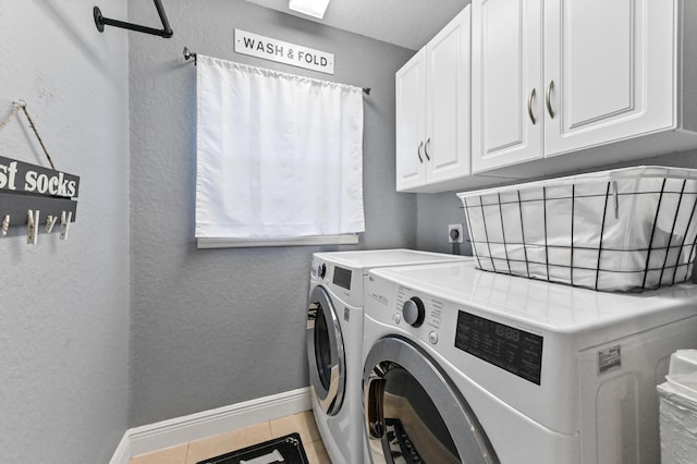 laundry room with cabinets, tile patterned flooring, and washer and clothes dryer