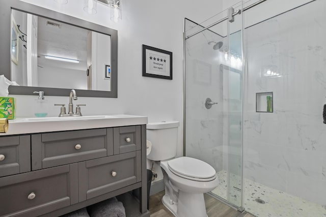 bathroom featuring hardwood / wood-style flooring, vanity, toilet, and a shower with door