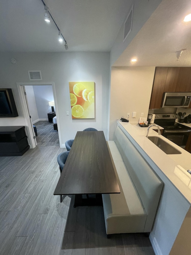 dining space featuring rail lighting, light wood-type flooring, and sink