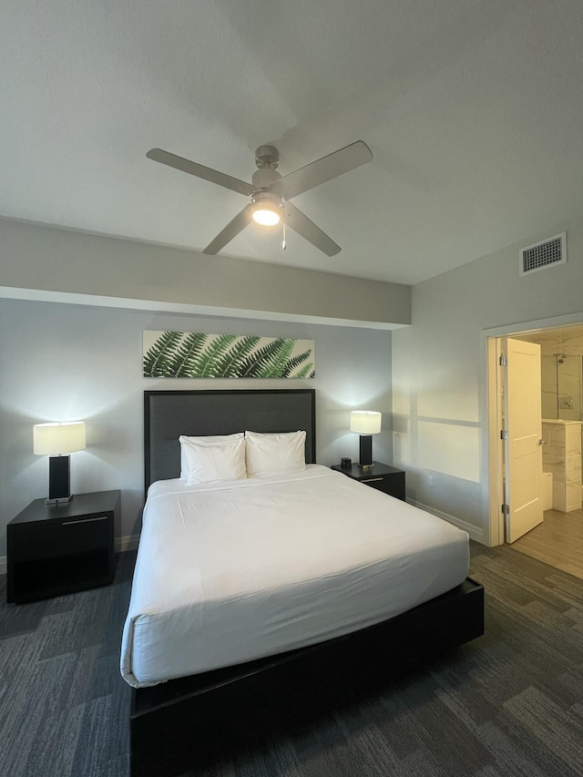 bedroom with ensuite bath, dark carpet, and ceiling fan