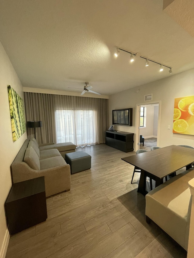 living room with ceiling fan, plenty of natural light, a textured ceiling, and light hardwood / wood-style flooring