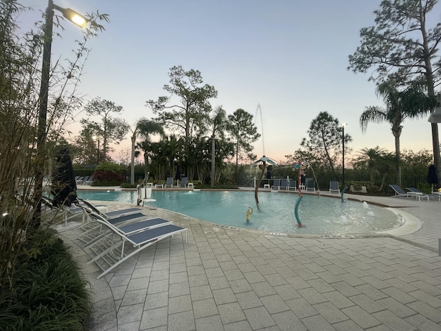 pool at dusk featuring a patio area