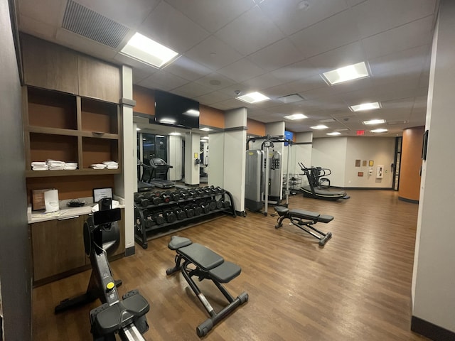 gym featuring a paneled ceiling and hardwood / wood-style flooring