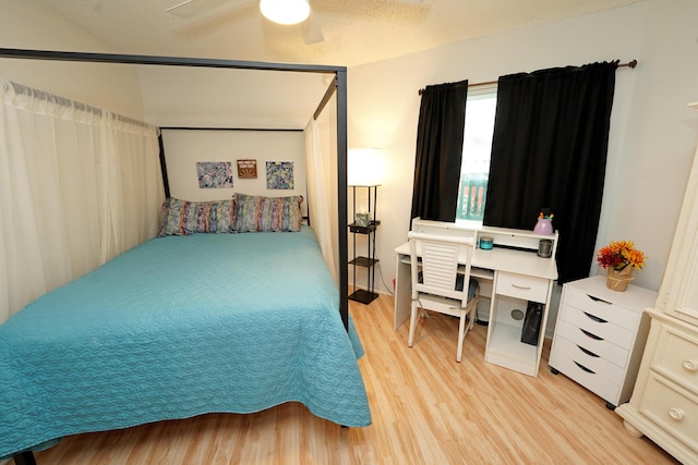 bedroom with a textured ceiling, ceiling fan, and light wood-style flooring