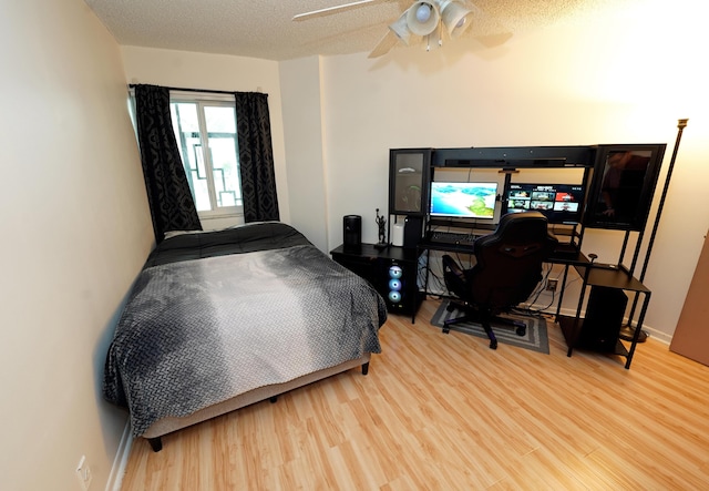 bedroom featuring light wood-type flooring, a textured ceiling, and ceiling fan