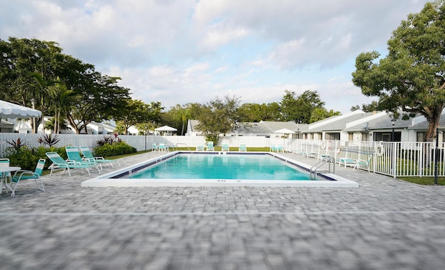 community pool with a patio area, a residential view, and fence