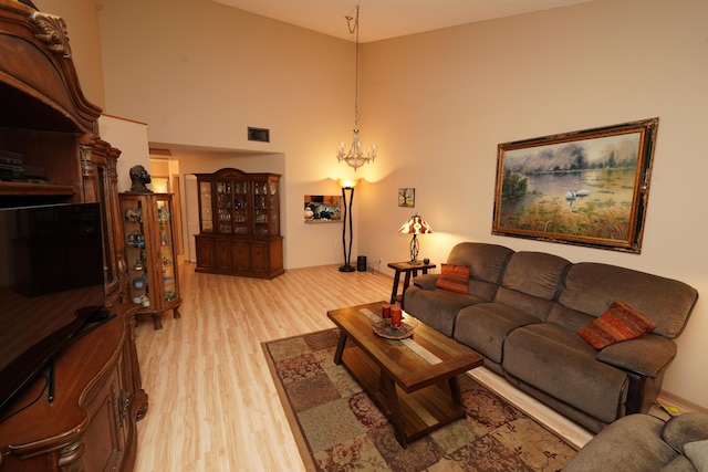 living area with a high ceiling, light wood-style flooring, visible vents, and a chandelier