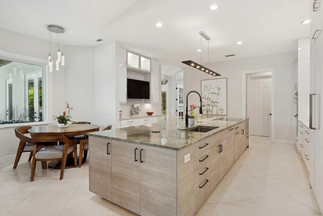 kitchen featuring sink, light stone countertops, pendant lighting, and a spacious island