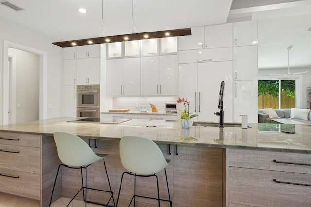 kitchen featuring a large island, white cabinetry, and light stone counters