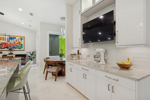 bar featuring white cabinets, pendant lighting, light stone counters, and lofted ceiling