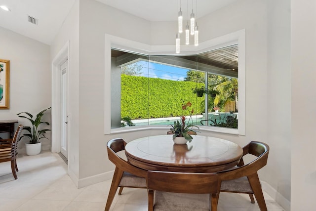 tiled dining space with vaulted ceiling and a healthy amount of sunlight