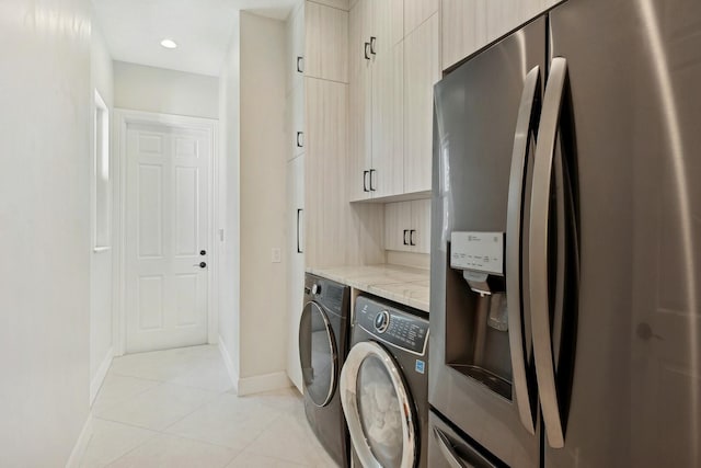 washroom featuring cabinets, light tile patterned flooring, and washing machine and clothes dryer