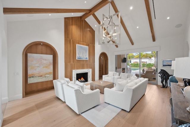 living room with beamed ceiling, an inviting chandelier, light hardwood / wood-style floors, and high vaulted ceiling