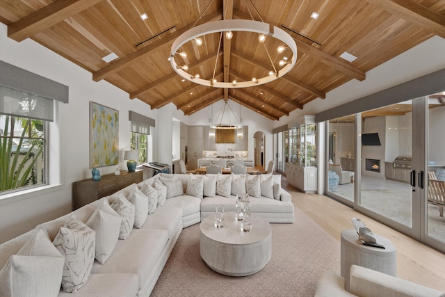 living room featuring beamed ceiling, wooden ceiling, high vaulted ceiling, and a chandelier