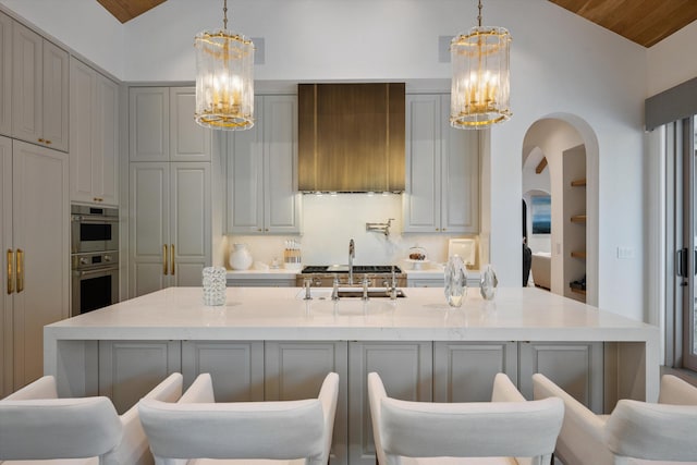 kitchen featuring gray cabinets, premium range hood, lofted ceiling, and a kitchen island with sink