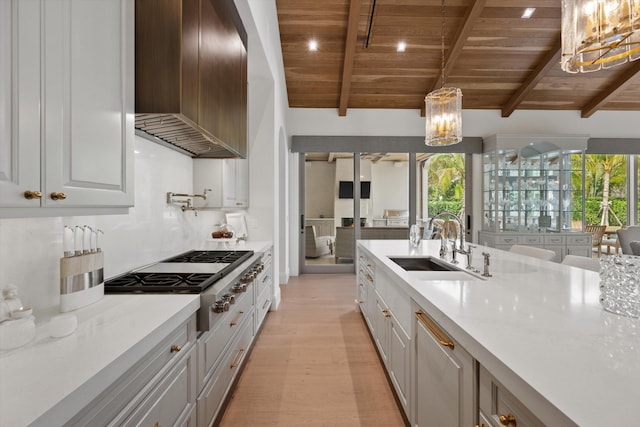 kitchen featuring white cabinetry, wooden ceiling, decorative light fixtures, stainless steel gas stovetop, and custom exhaust hood