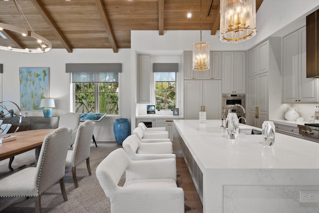 kitchen featuring a large island, wooden ceiling, beamed ceiling, decorative light fixtures, and gray cabinets