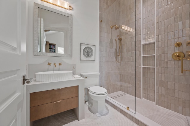 bathroom with tile patterned flooring, vanity, tiled shower, and toilet