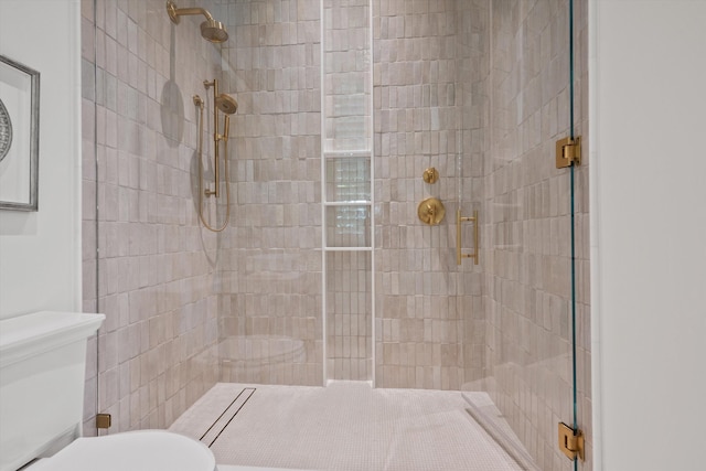 bathroom featuring a shower with door and toilet