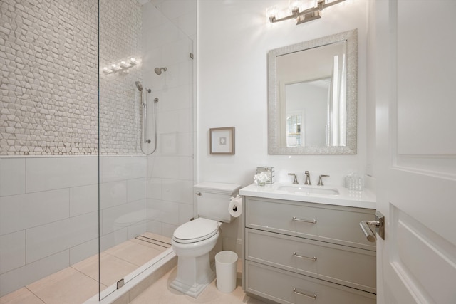 bathroom featuring tile patterned flooring, toilet, vanity, and tiled shower