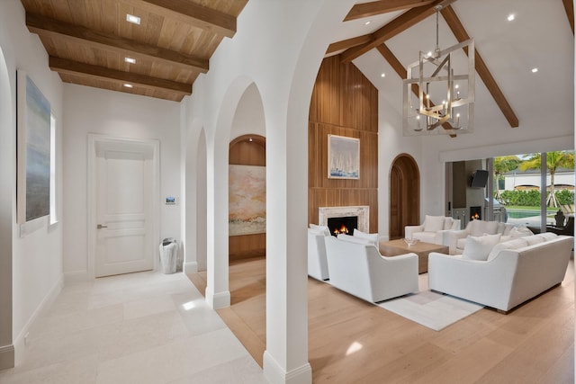 living room with beamed ceiling, a notable chandelier, wood ceiling, and high vaulted ceiling